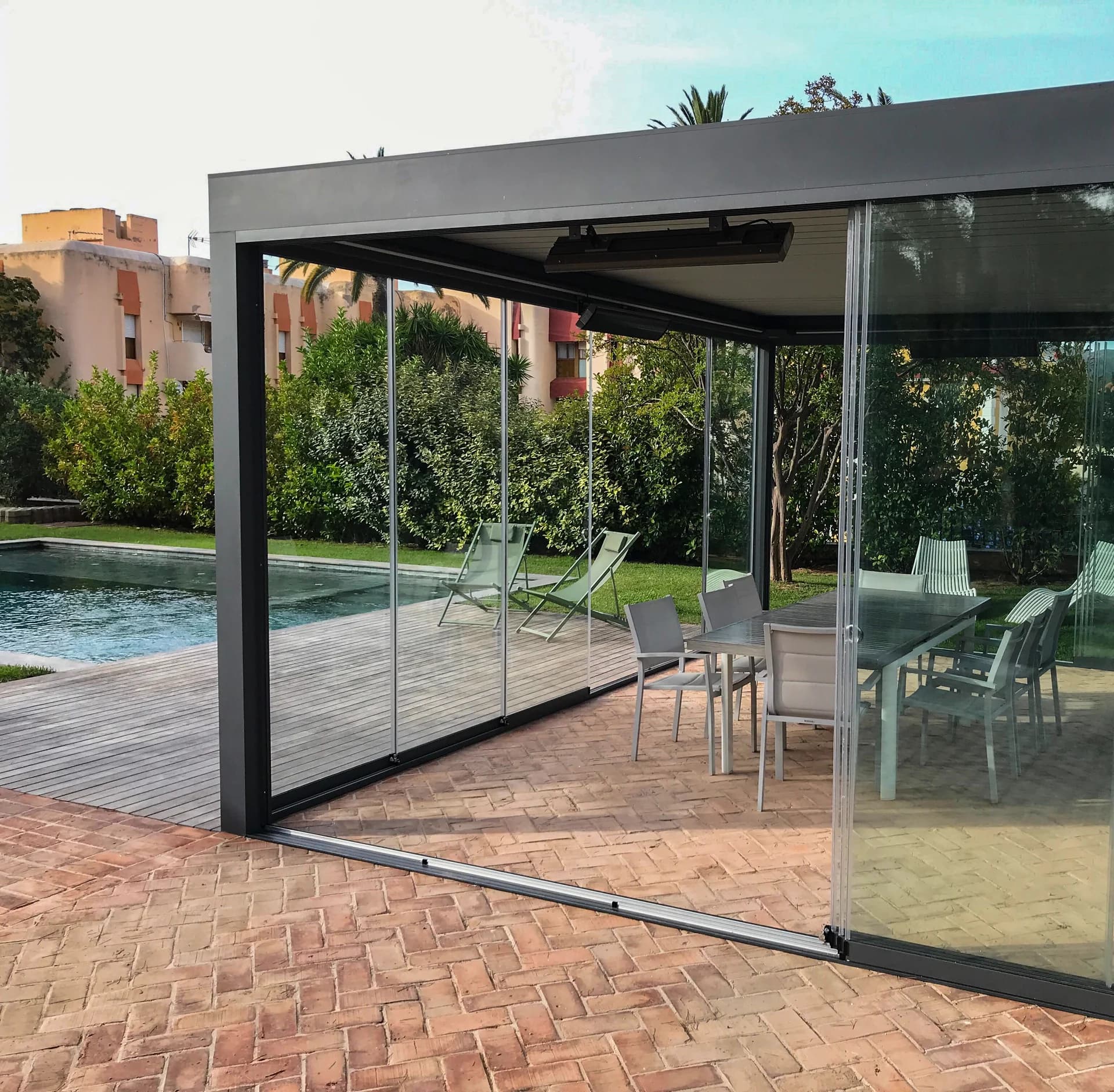 Exemplo de pérgola com painéis de vidro deslizantes junto a uma piscina