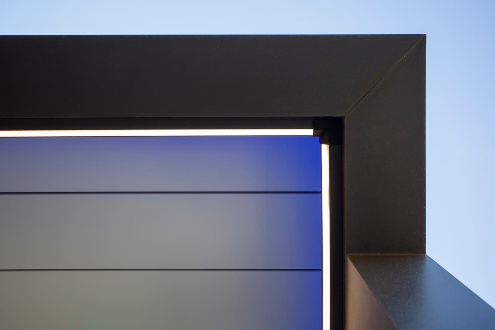 Fita LED acesa no perímetro de uma pérgola escura, com luz azul