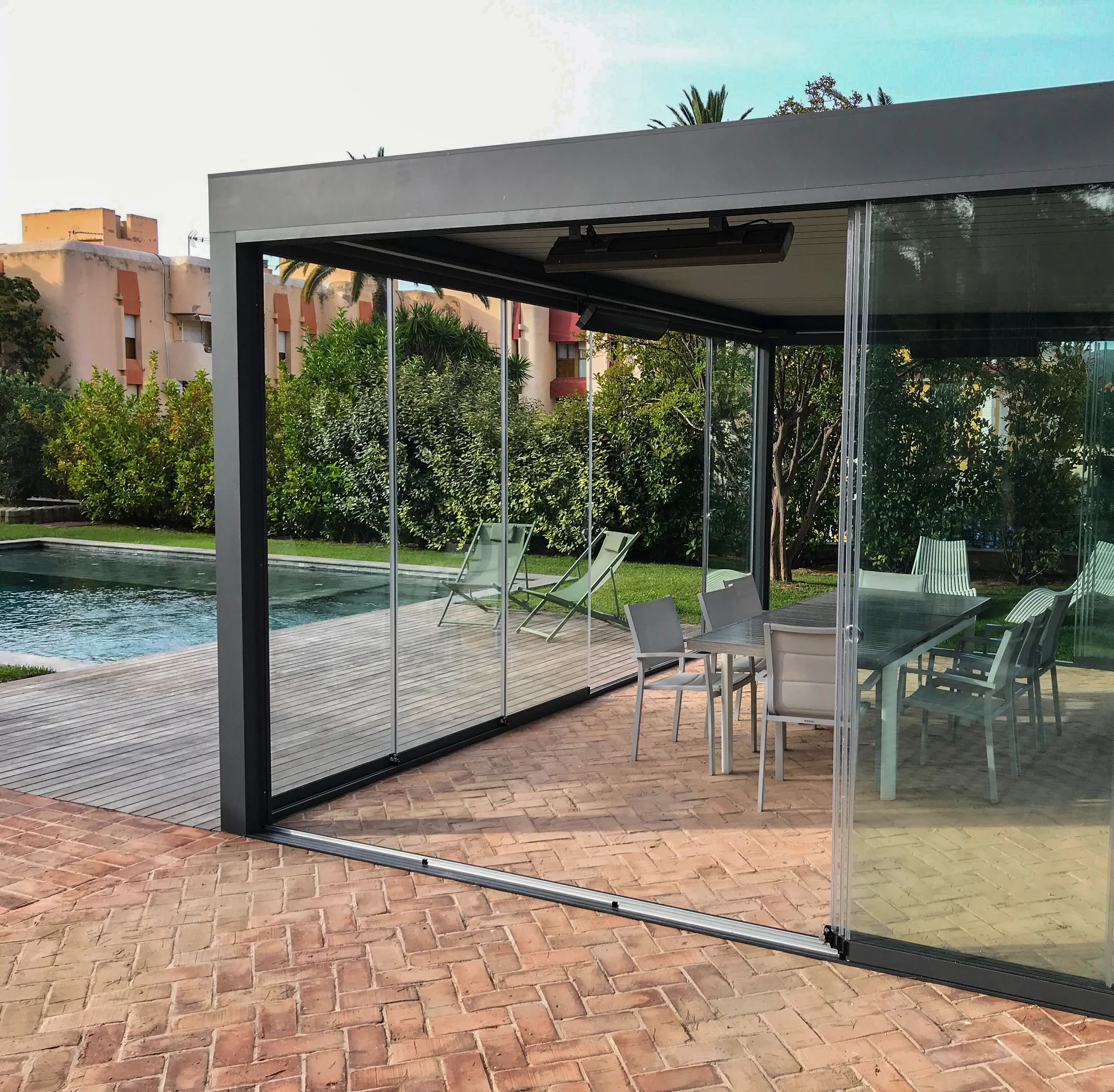 Example of a pergola with sliding glass panels beside a swimming pool